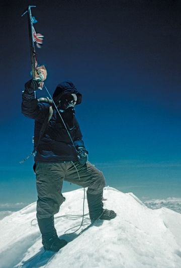 Tenzing Norgay brandishes his ice axe on the summit of Mount Everest. 